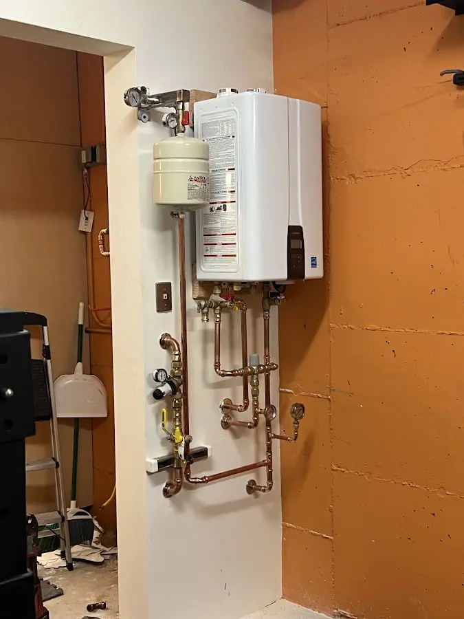 Plumbing technician inspecting water heater connections in Sodus